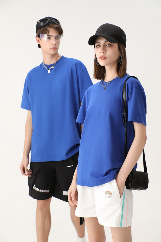 Male and female models wearing matching blue cotton crew neck T-shirts, paired with casual outfits. The minimalist design of the shirts offers a comfortable and stylish look for both men and women.